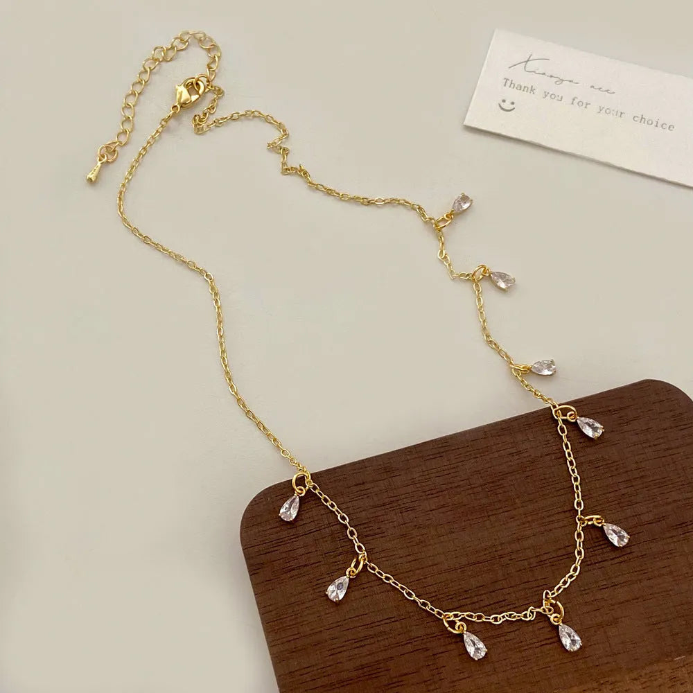 Zircon three-piece jewellery set with geometric meteor shower pendant necklace, matching earrings, and anklet.