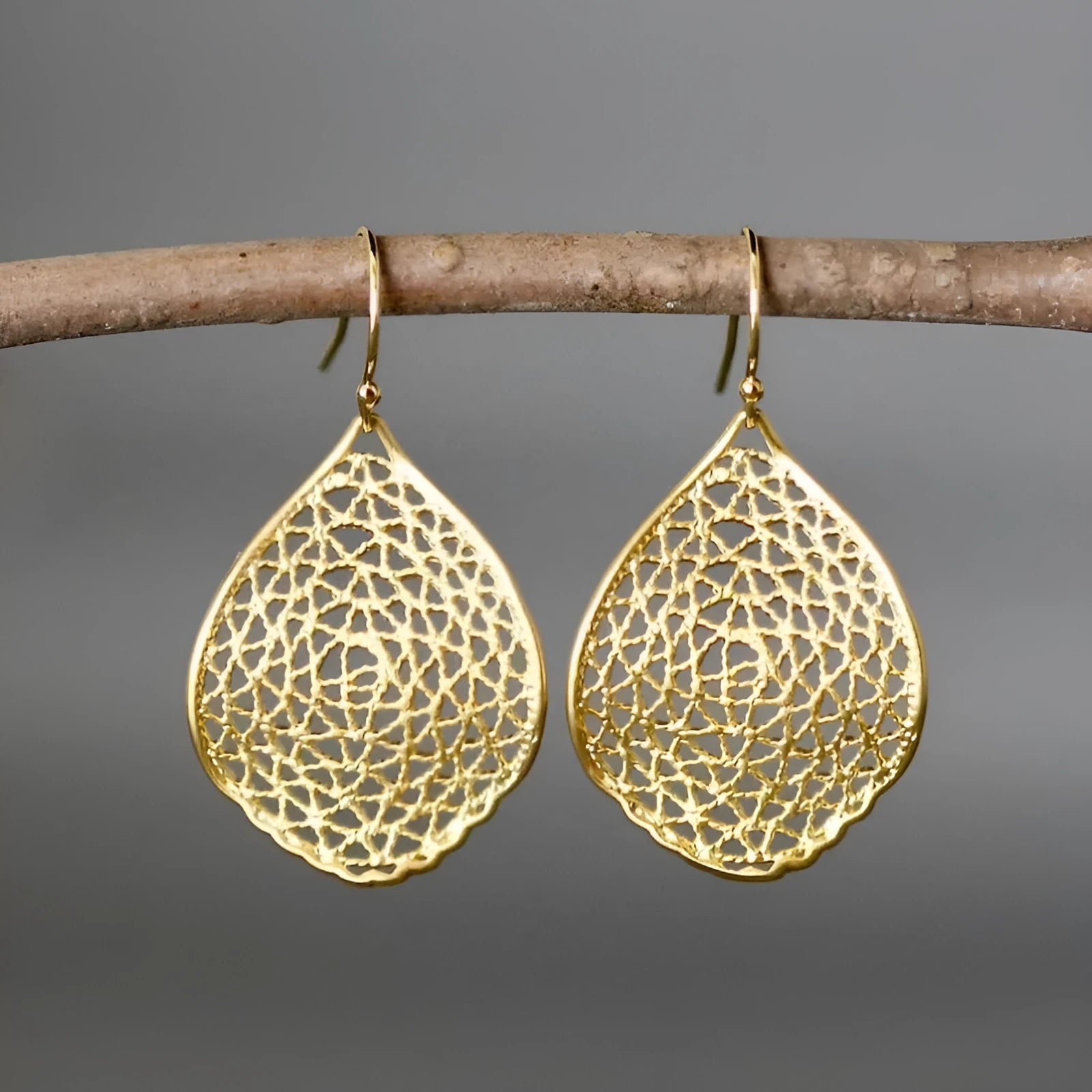 Gold-coloured retro-style drop earrings with a detailed hollow leaf pendant design.