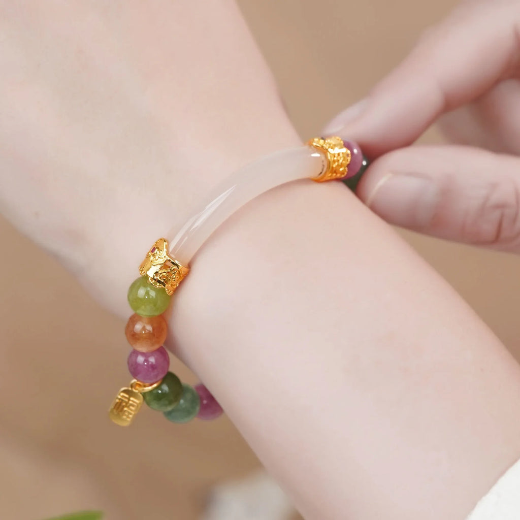 Natural rainbow-coloured tourmaline and jade half bracelet for women on a wrist.