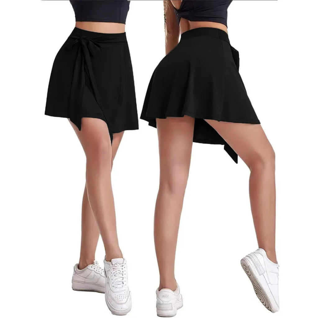 Black thigh-length sports skirt with high waist and shoulder strap detail on a model.