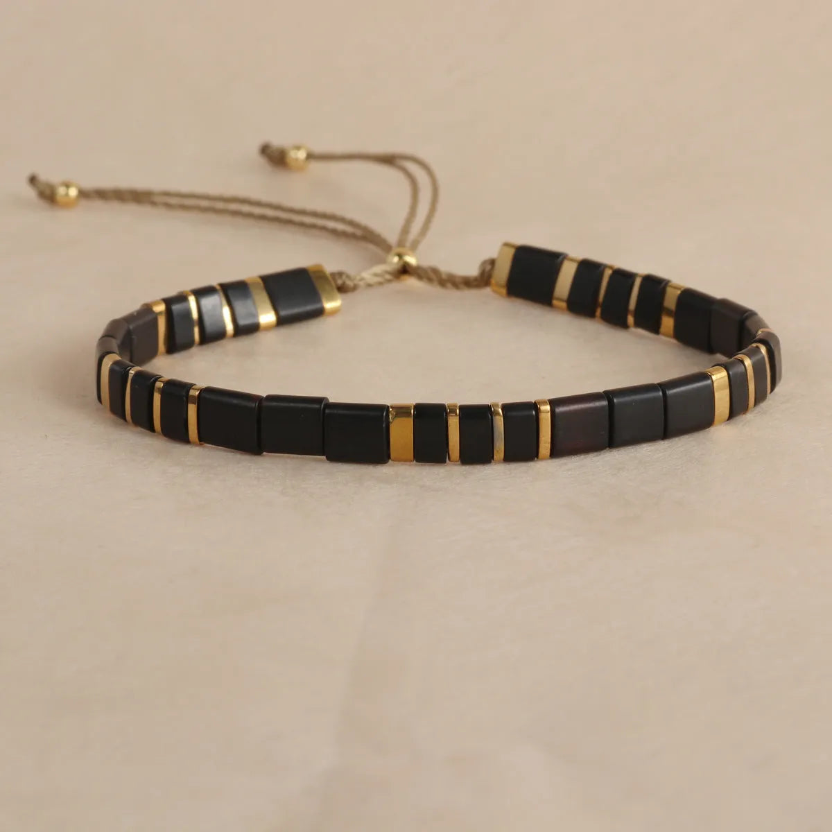 Adjustable geometric beaded bracelet with pull beads in milky white, black, green, blue or red.