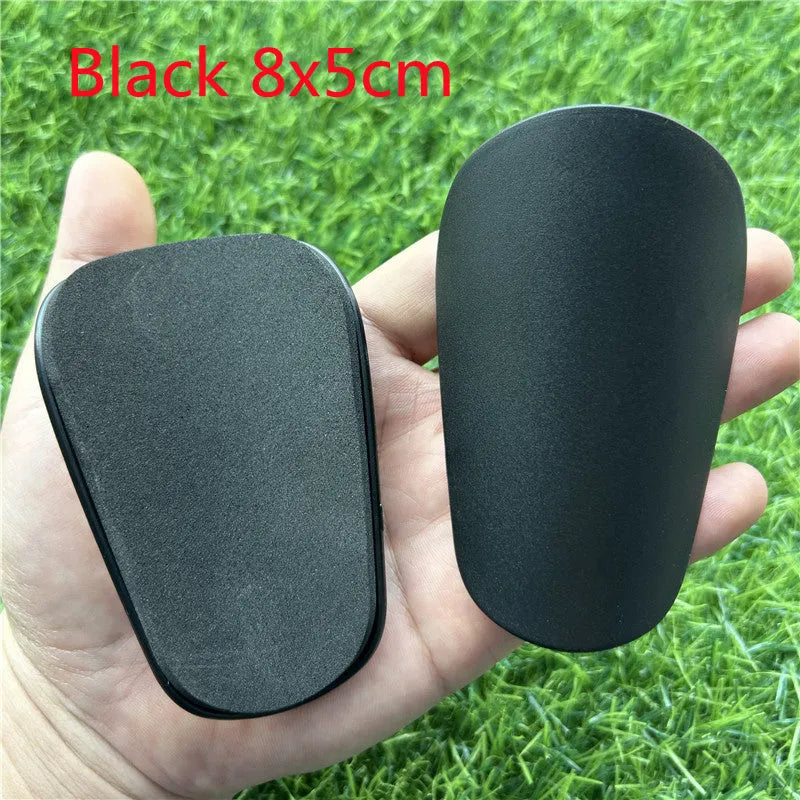 Extra small mini football shin guards measuring 8cm by 5cm in black and white plastic