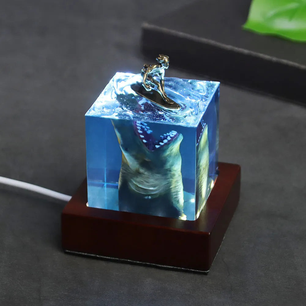 Clear epoxy resin shark surfer night light ornament with LED base in 5cm and 8cm sizes.
