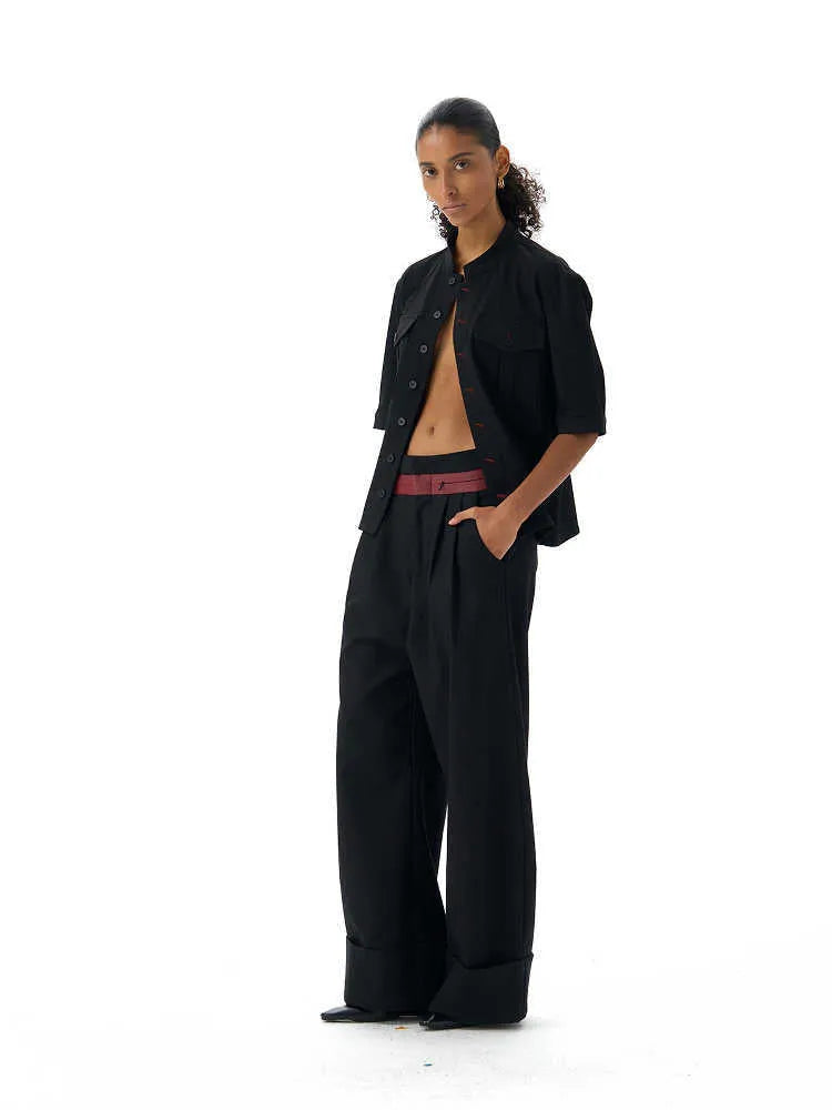 A black handmade half sleeve shirt with a shirt collar, shown on a hanger.