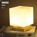 Nordic white geometric table lamp with solid wood base and USB charging port on a wooden desk.