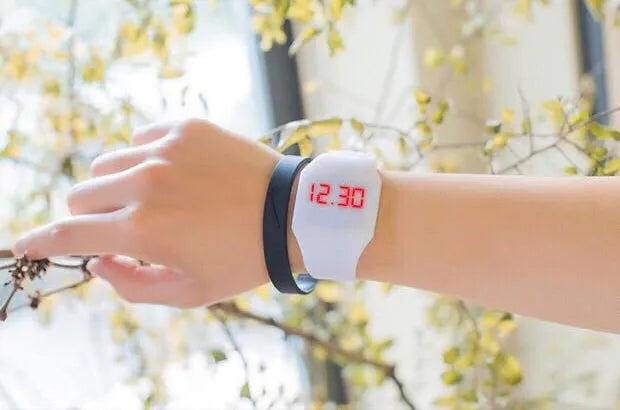 Square electronic touch screen watch with plastic case and PU strap on a wrist.