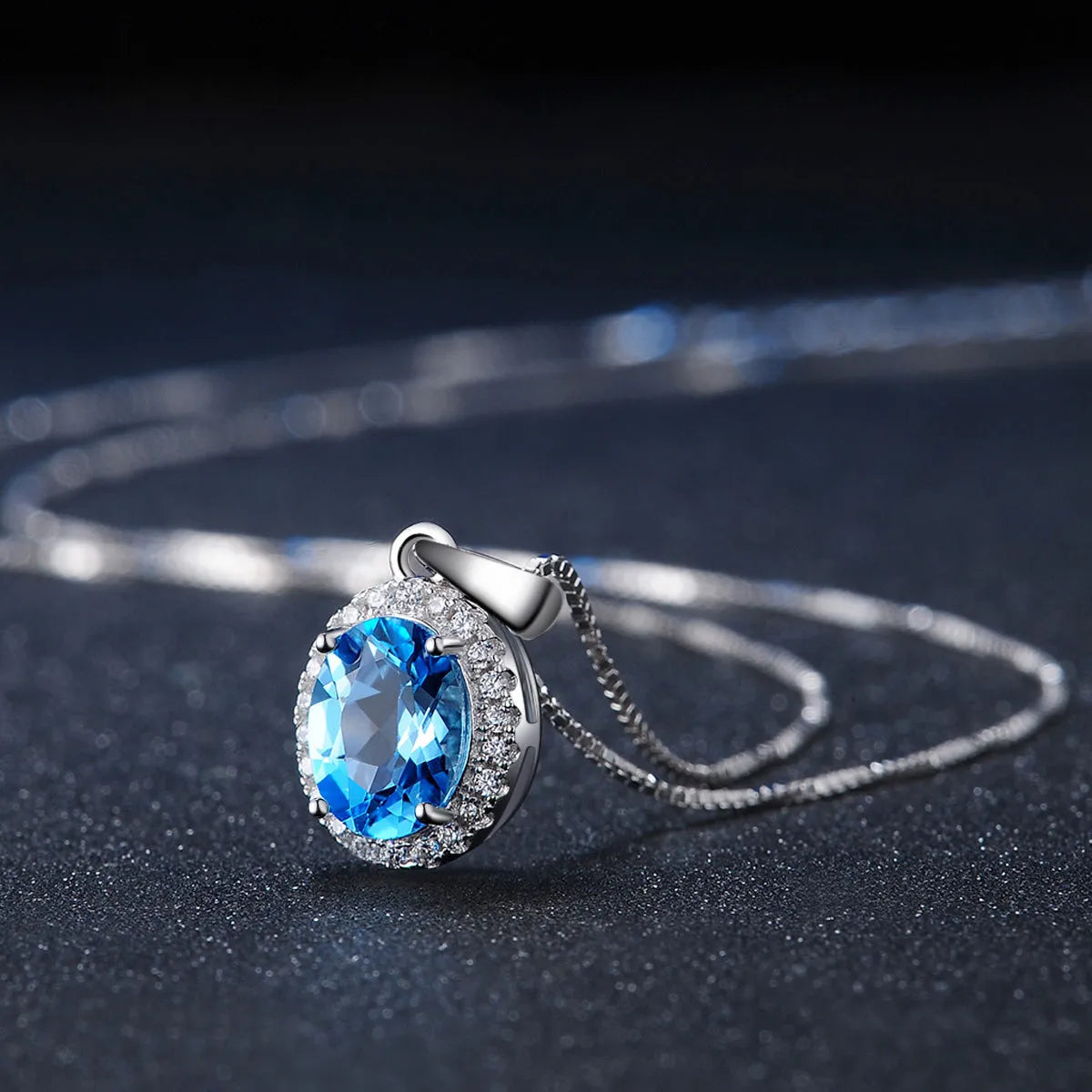 A four-piece women's sterling silver jewellery set with blue topaz gems, showing geometric earrings, ring, pendant, and necklace.