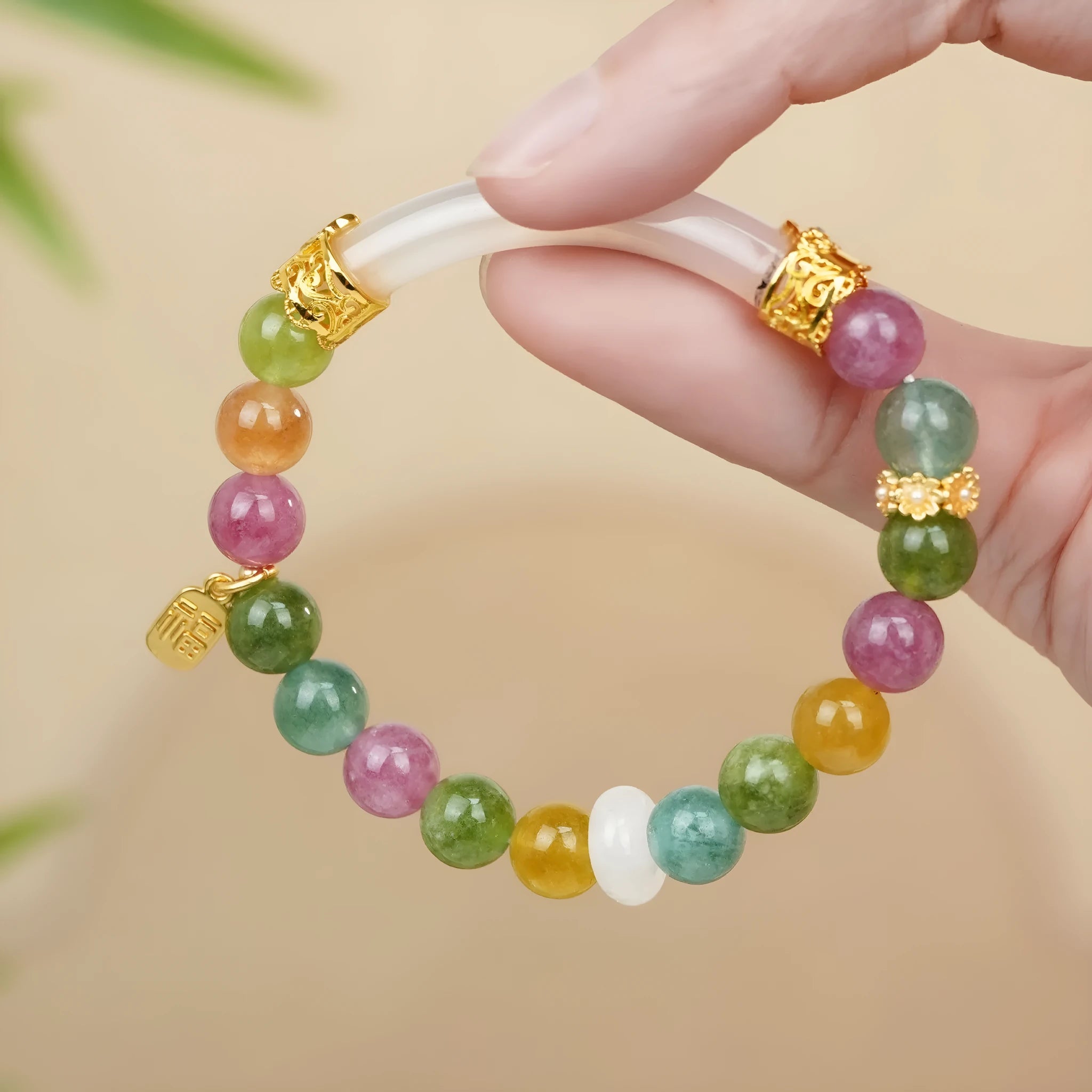 Natural rainbow-coloured tourmaline and jade half bracelet for women on a wrist.