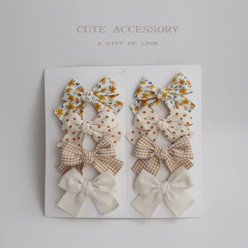 Children's cloth dovetail bow hairclip set showing eight colour pattern options