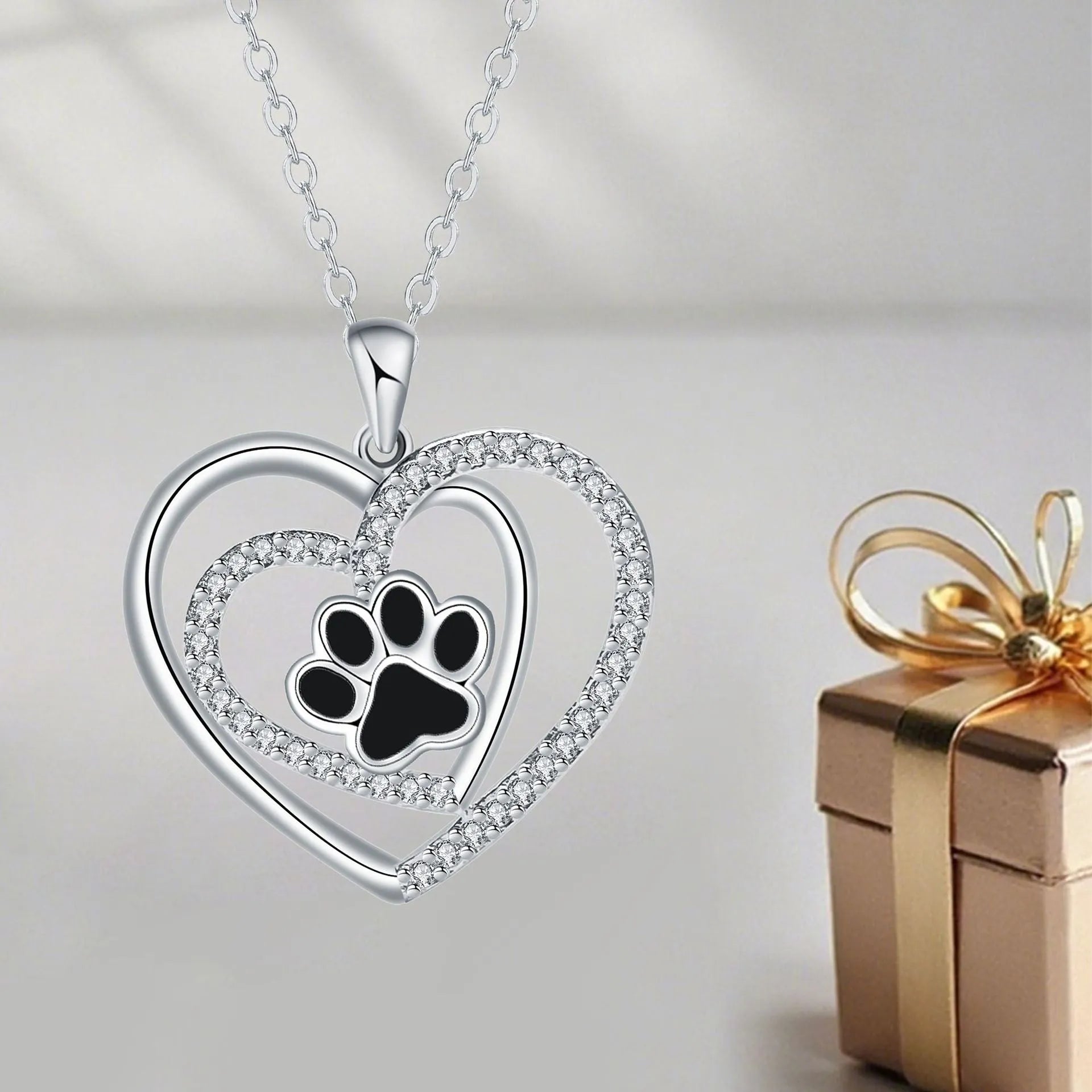 Gold tone dog paw print and heart charm necklace on a cross chain for women.