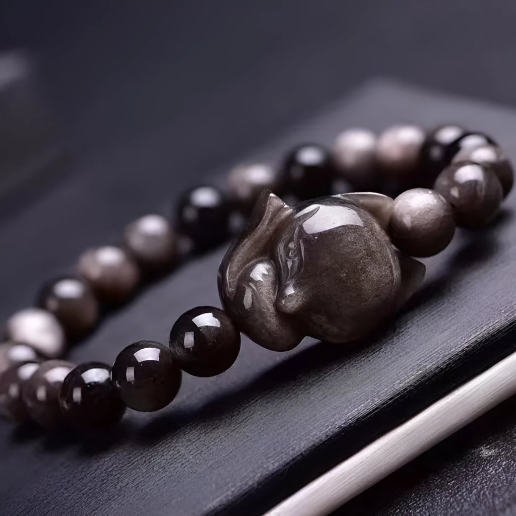 Women's obsidian bracelet with a single 8mm polished bead and a silver fox charm on an adjustable leather cord.