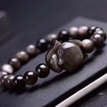 Women's obsidian bracelet with a single 8mm polished bead and a silver fox charm on an adjustable leather cord.