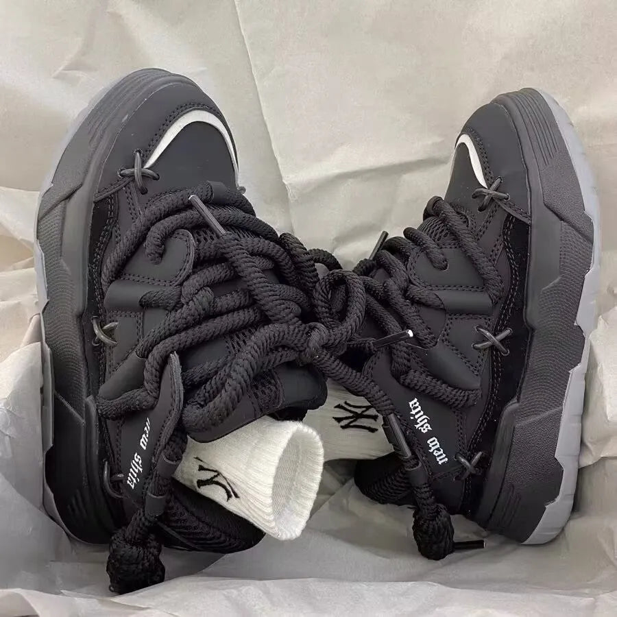 Women's black platform sneakers with thick rubber sole and lace-up front, showing round toe and chunky retro design