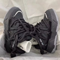 Women's black platform sneakers with thick rubber sole and lace-up front, showing round toe and chunky retro design