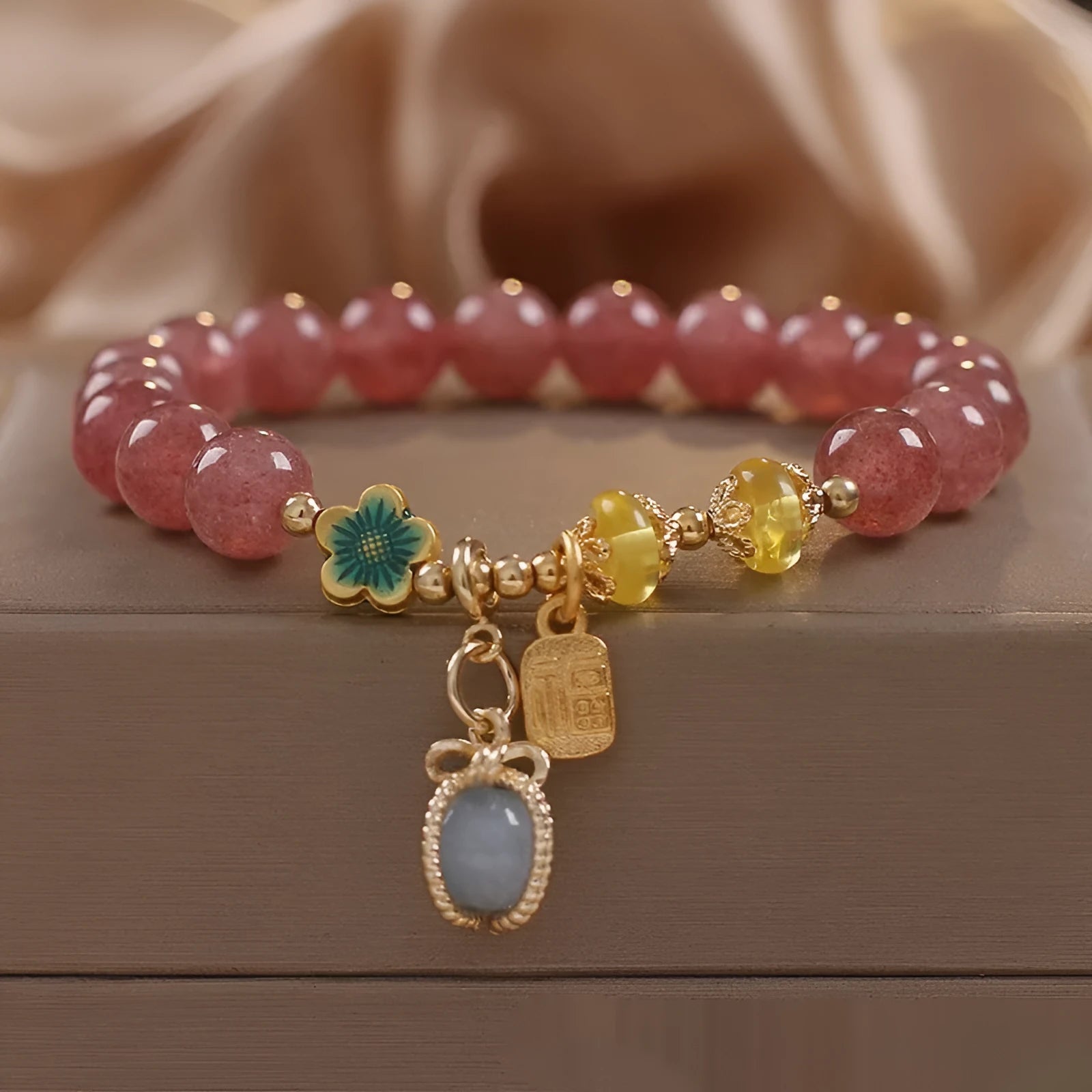 Red bracelet with strawberry quartz beads, alloy metal spacers, and rhinestone decorative details.