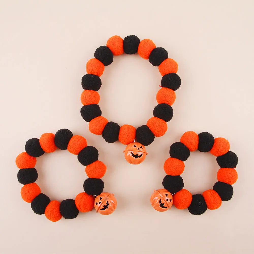 Orange pumpkin print cat collar with plastic buckle and small metal bell attached.