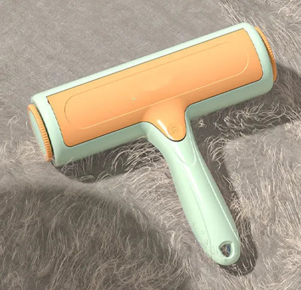 Two-way roller pet hair removal brush in green orange colour with ABS body and nylon fibre bristles on a beige sofa