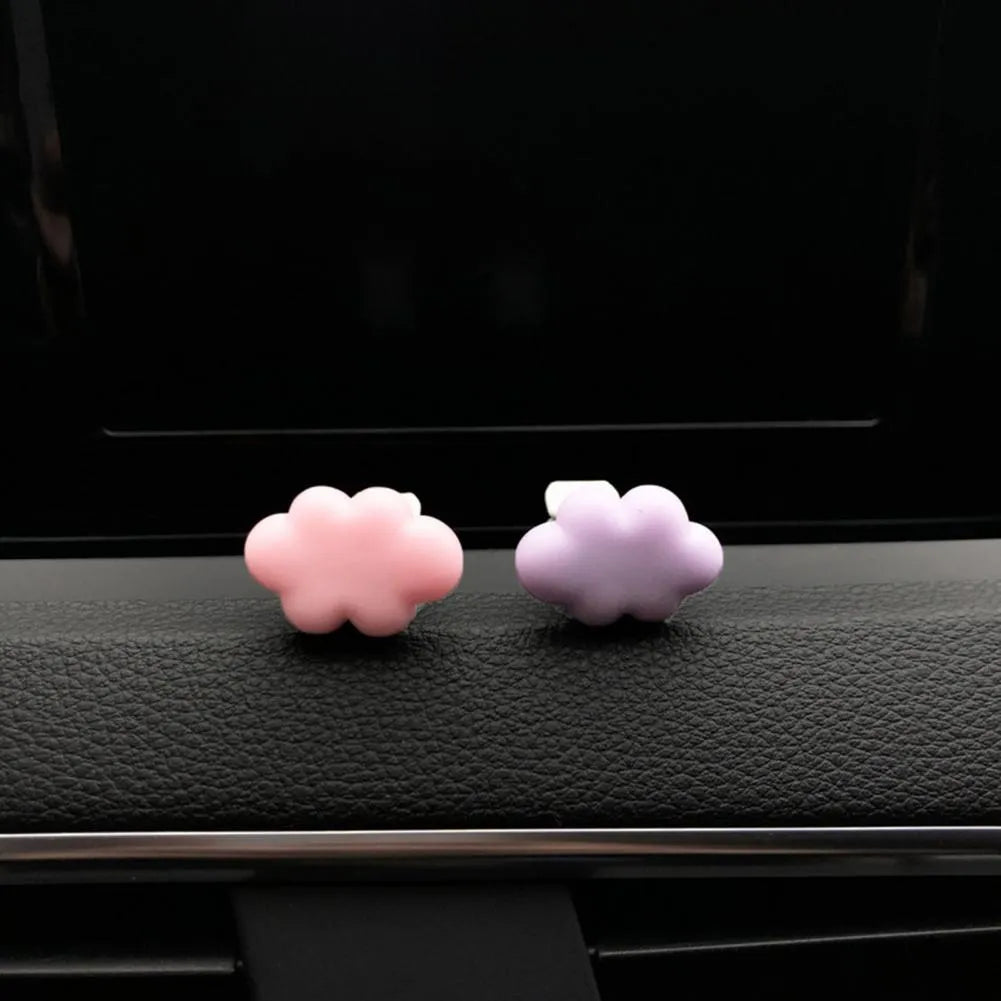 Small colourful resin car fragrance clip shown in multiple colours on a car air vent.