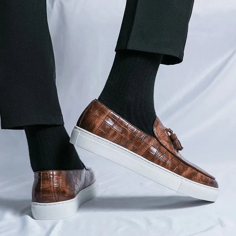 Men's black tassel detail slip-on sneakers with a round toe and rubber sole on a white background.