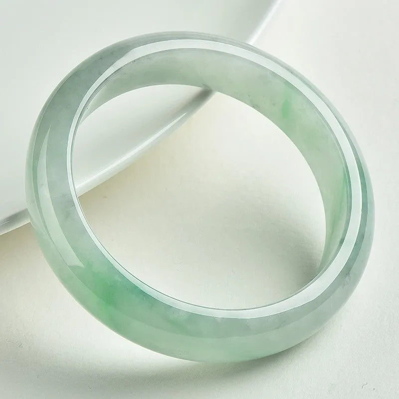 Light green jade bracelet on wrist, natural style, showing sizing scale from 53mm to 64mm