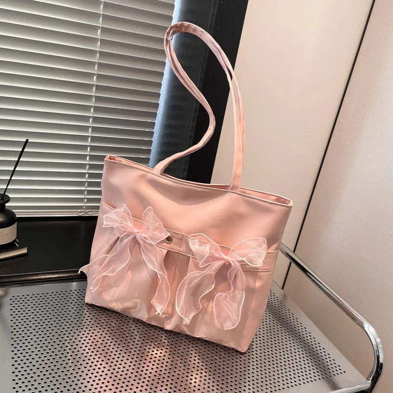 Black college-style tote bag with large capacity, a bow detail, and two shoulder straps.