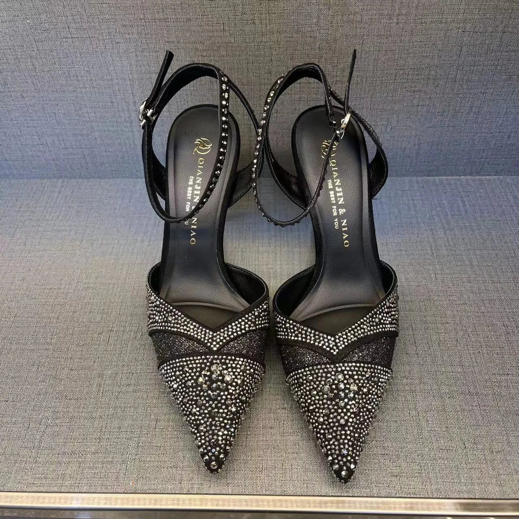Women's black high heel shoe with a red sole, pointed toe, and a hollow stiletto heel on a plain background.