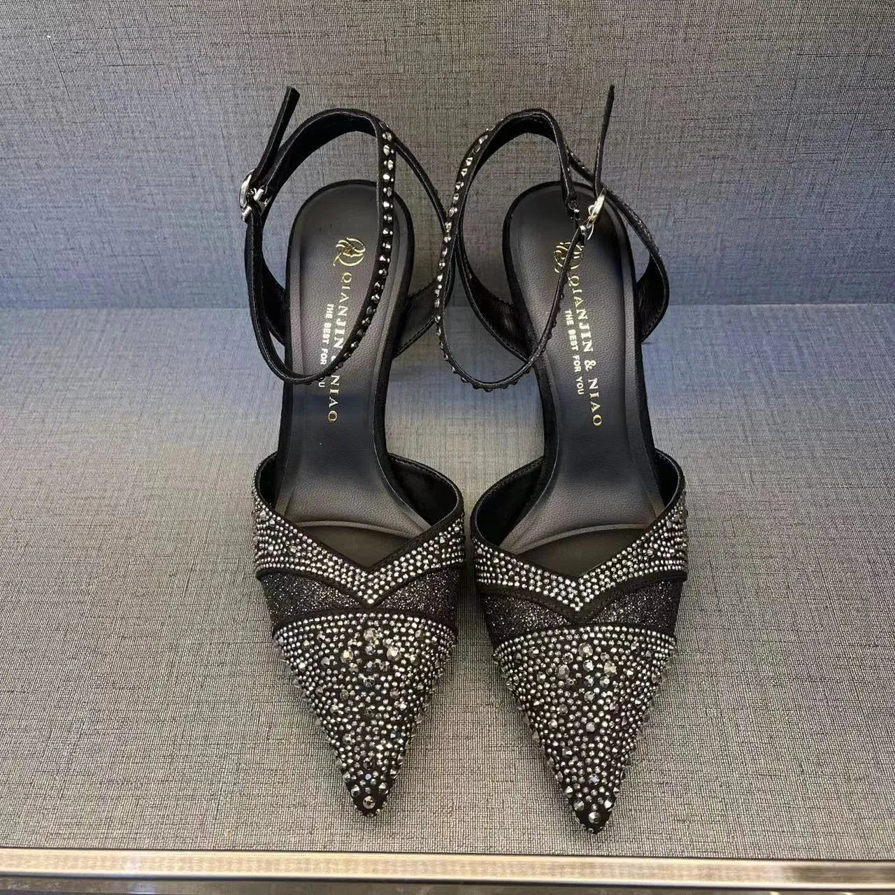 Women's black high heel shoe with a red sole, pointed toe, and a hollow stiletto heel on a plain background.