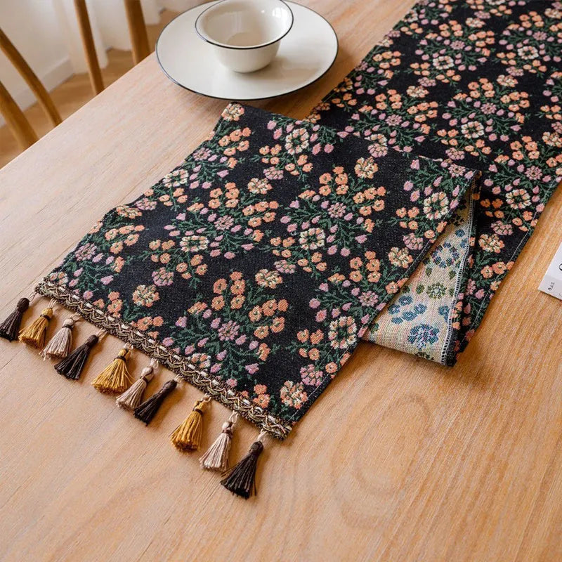 Dark blue striped jacquard table runner with tassel trim laid on a wooden table