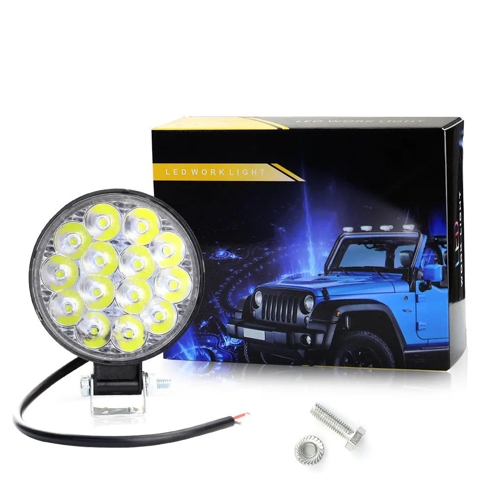 Compact round white LED work light with aluminium housing for car, truck, and off-road use.