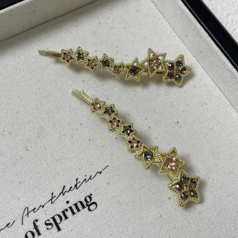 Gold-coloured Korean style hair barrette with a star and letter decoration, shown as a side clip for bangs.