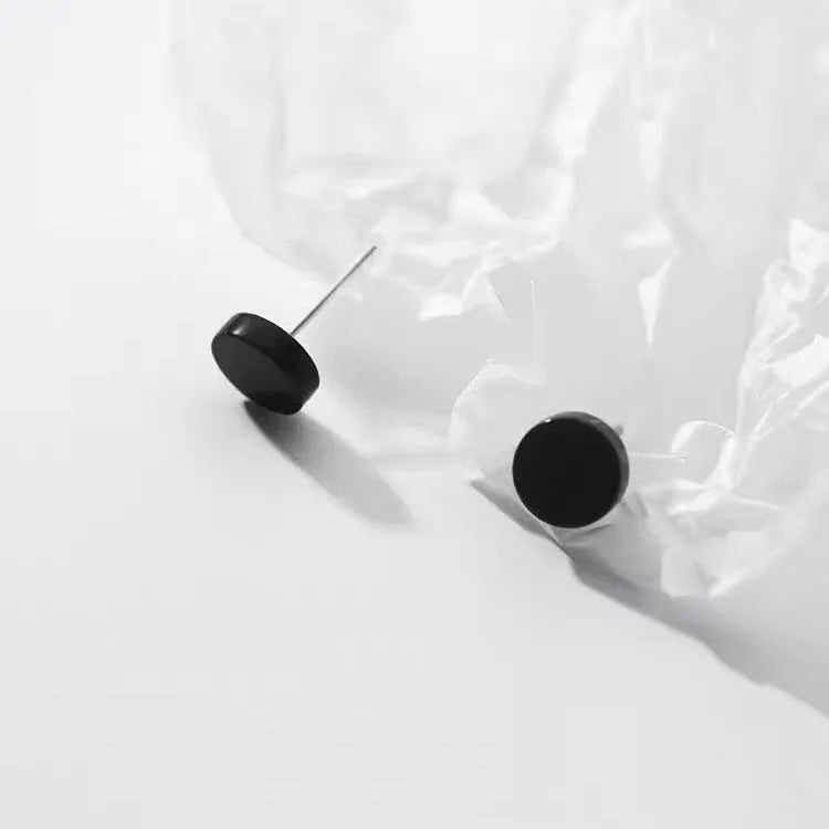 A pair of S999 sterling silver geometric round flat ear bone studs in black and silver finishes, showing size scale.