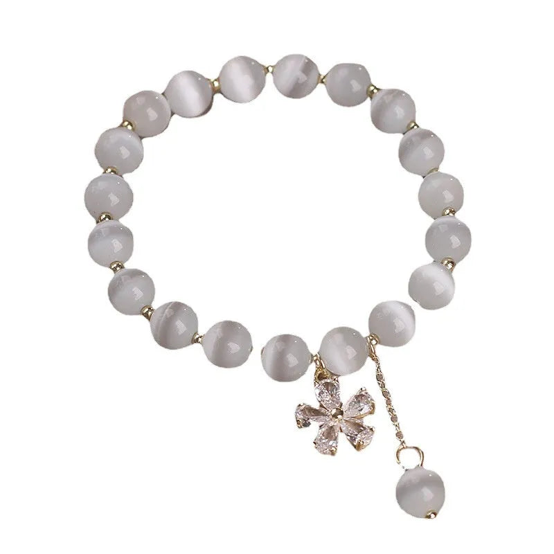White Cat's Eye stone bracelet with a small flower tassel pendant and a safety buckle.