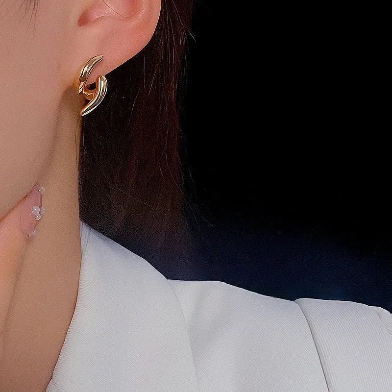 Women's textured line geometric copper stud earrings in silver and gold tones on neutral background