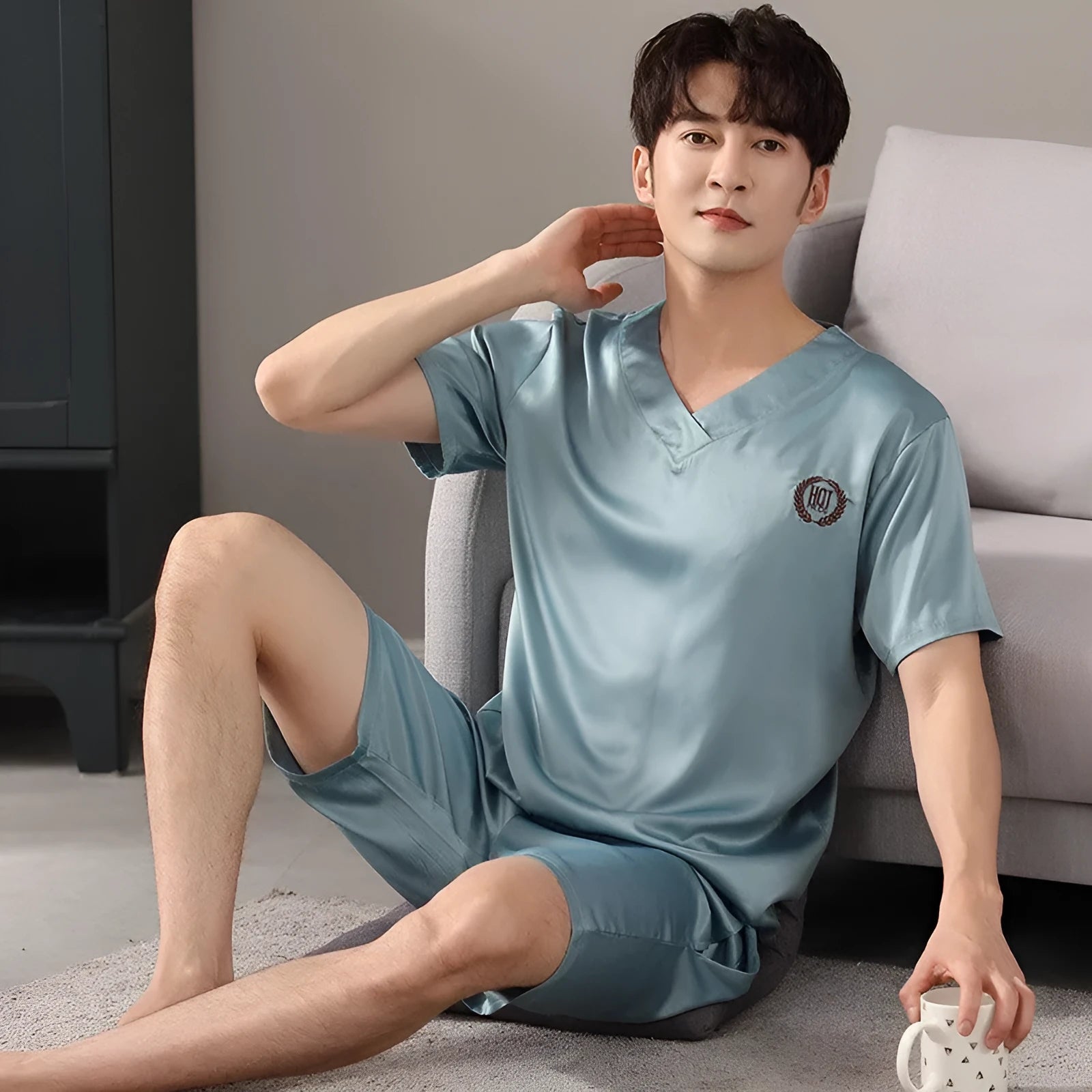 Man wearing a loose grey ice silk short-sleeve pyjama top and matching shorts.