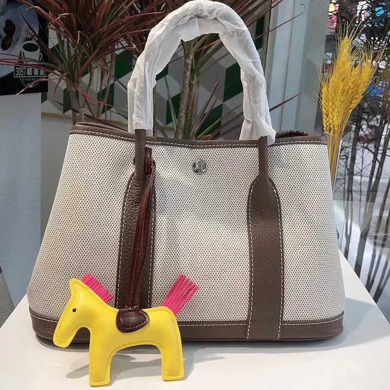 Women's canvas bucket tote bag with genuine leather trim showing open top and crossbody strap