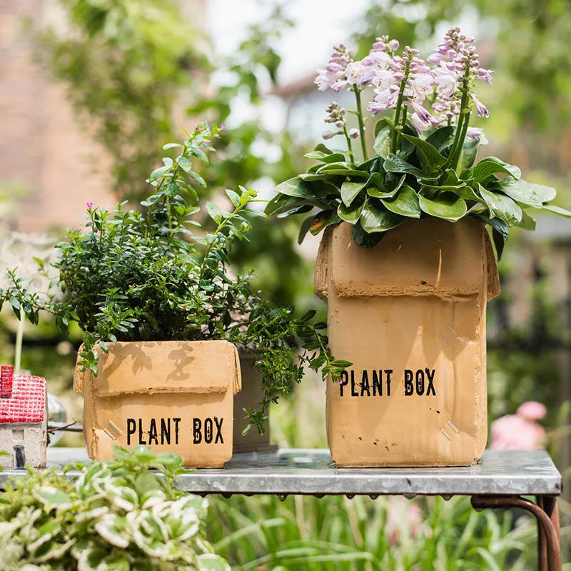 Cement brown paper box style flowerpot with angular sides and a perforated base on a floor.