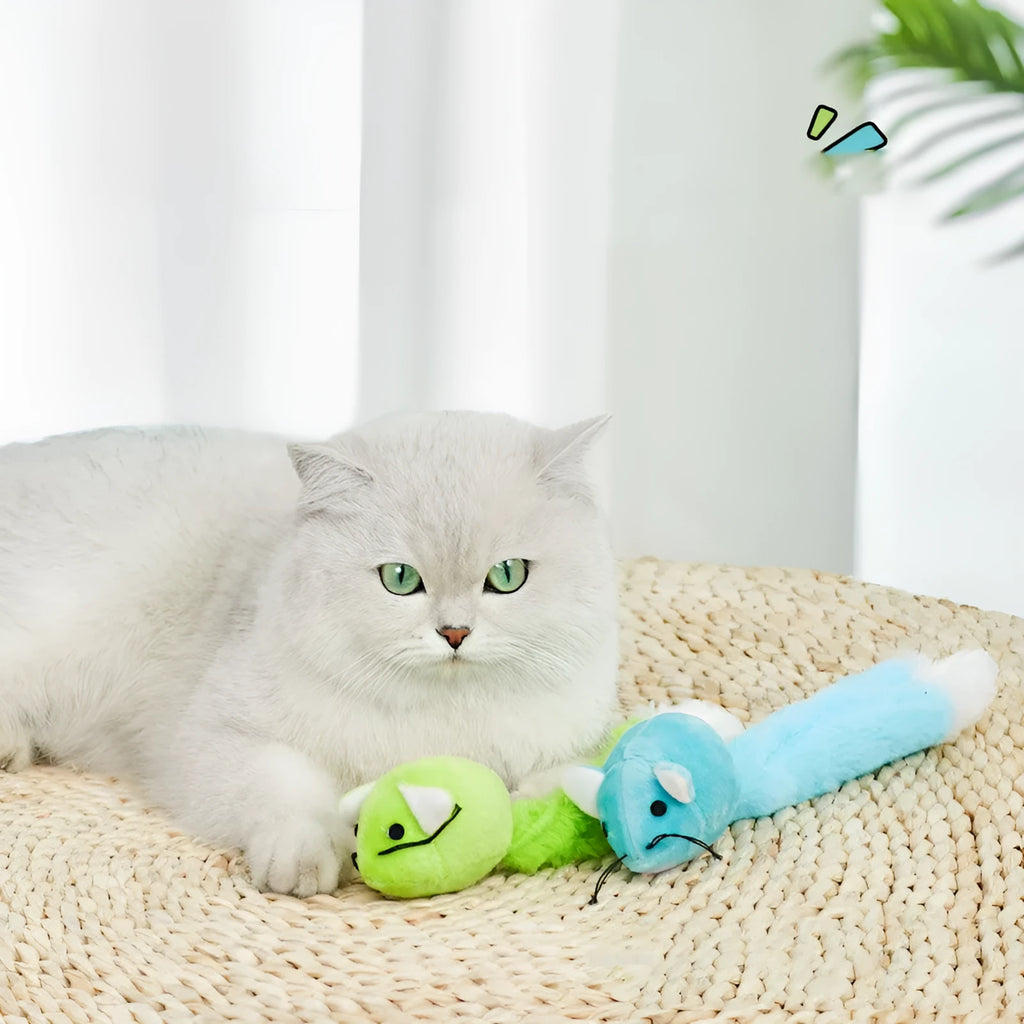 Three plush toy mice in green, pink, and blue with long tails, arranged on a surface