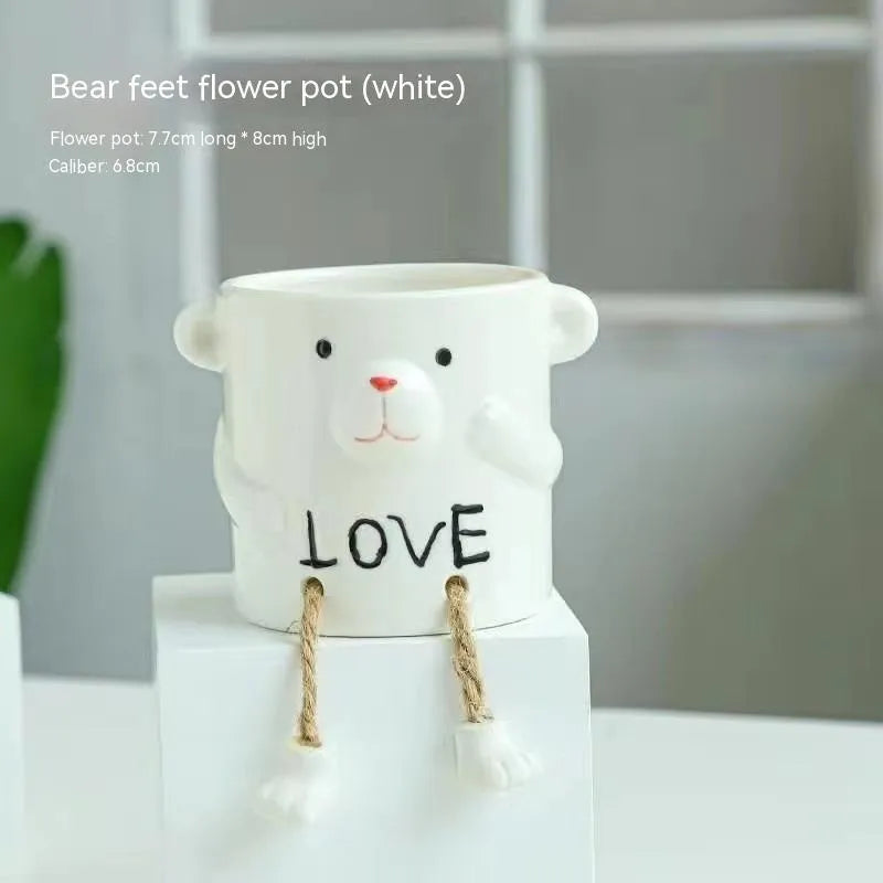 Ceramic hanging foot flowerpot in a cartoon style, shown on a desktop with a small succulent plant.
