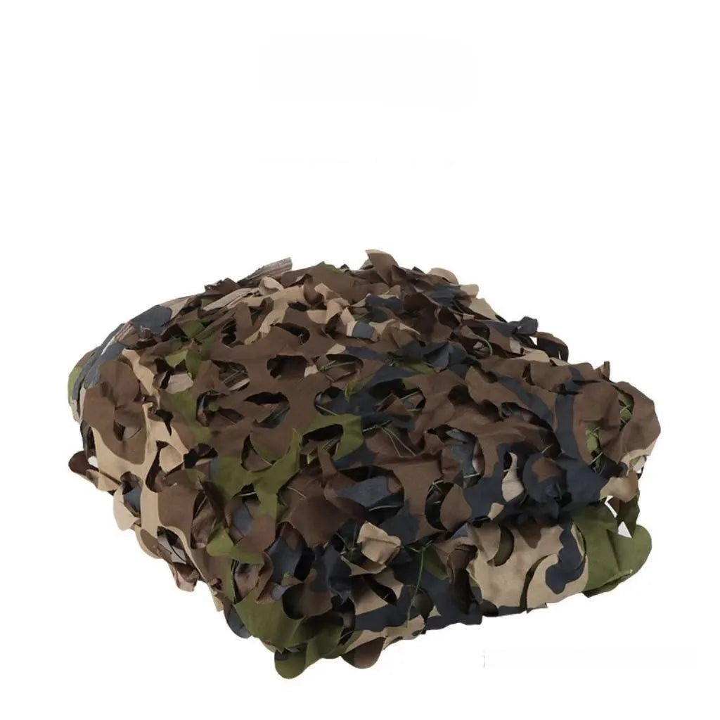 Green camouflage net cover on a forest floor, showing a multi-spot leaf pattern.
