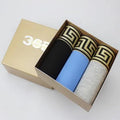 Three pairs of mens plain cotton boxer shorts in black, blue, and grey, folded together.