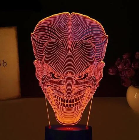 A 3D LED table lamp showing multiple colour lights, sitting on a square base with a USB cable and remote control.
