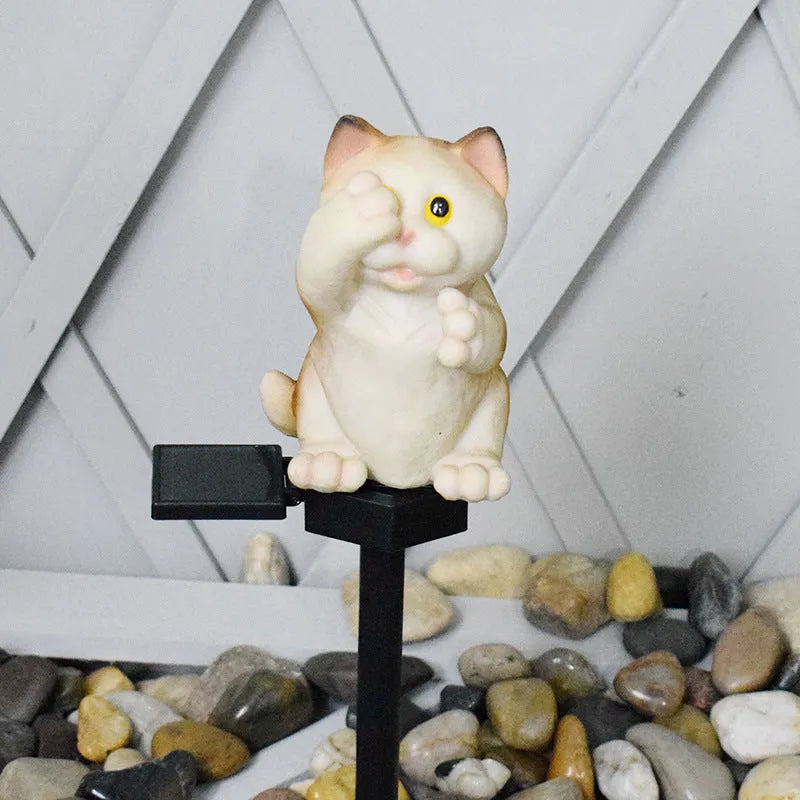 Brown resin solar-powered cat lawn light with LED illumination in a garden setting.