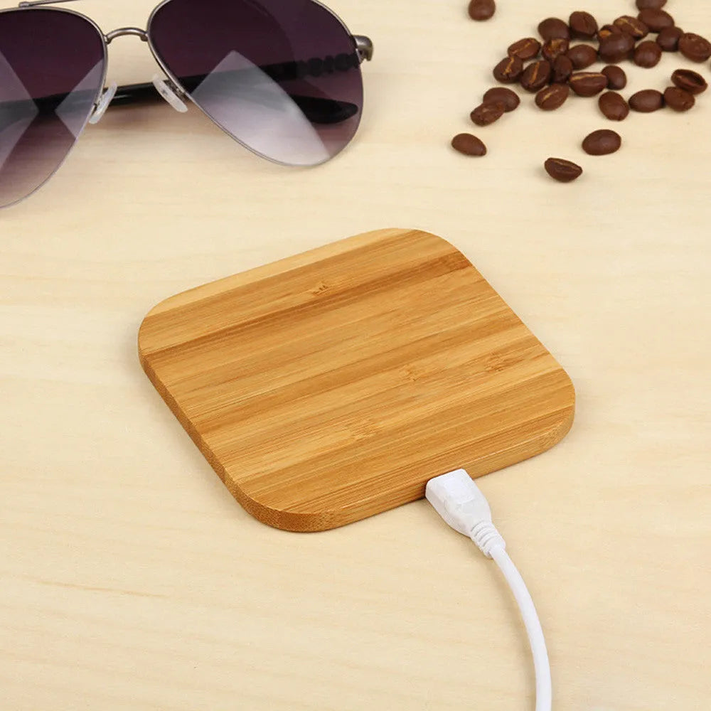 Square brown wooden bamboo 5W wireless charging pad for smartphones on a table.