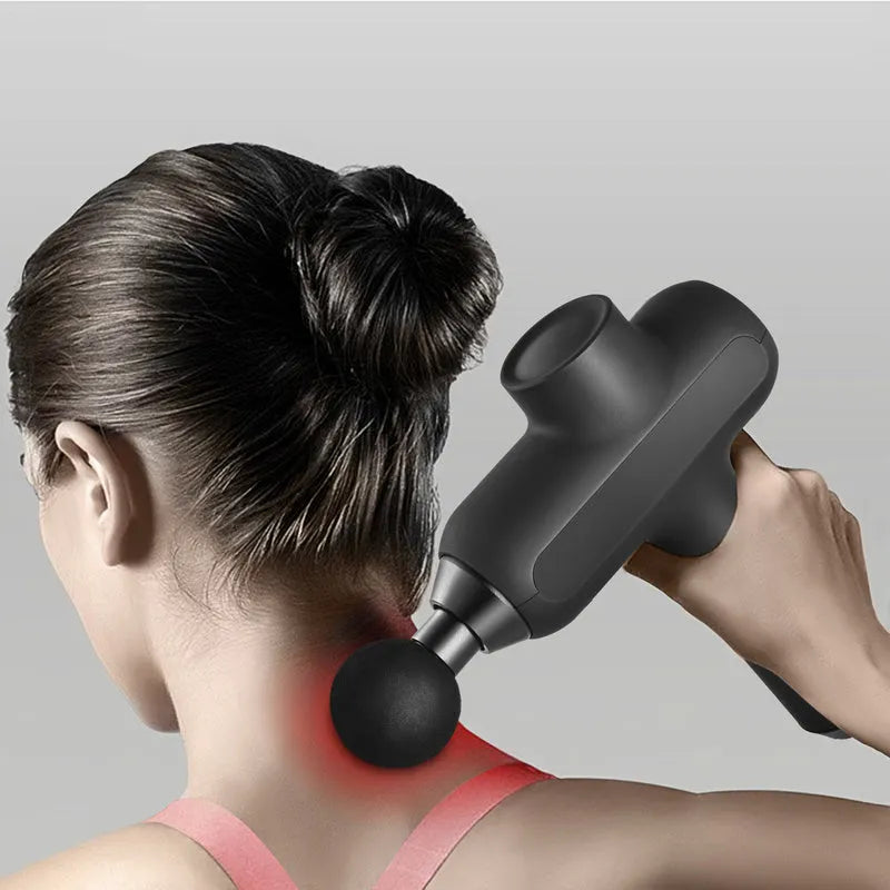 Handheld black muscle massager with six different coloured massage heads on a table.