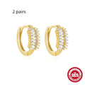 A pair of sterling silver stud earrings with a small round geometric drop design, shown in a gold tone finish.