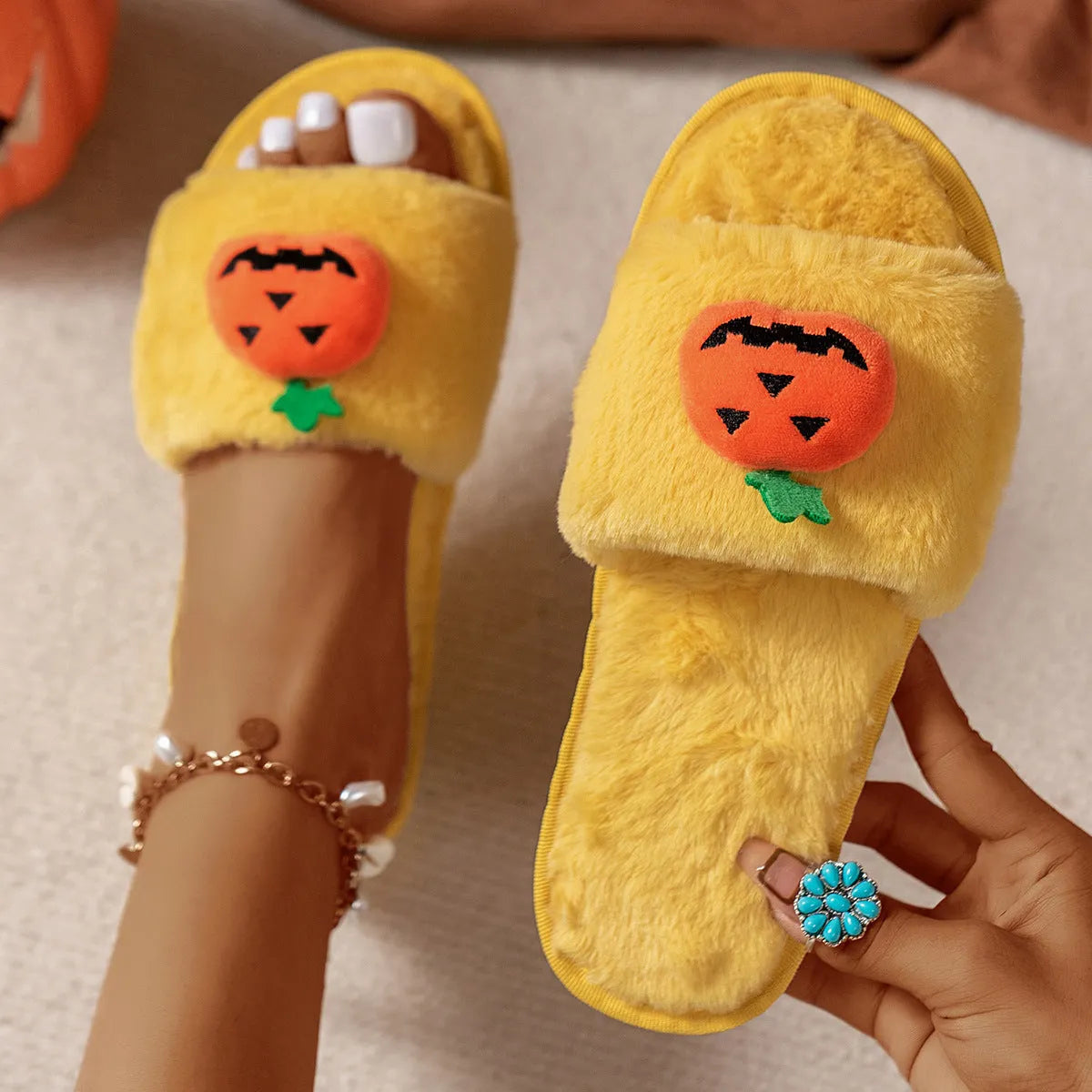 Yellow cartoon pumpkin plush slippers with open toe and anti-slip sole on a white background.