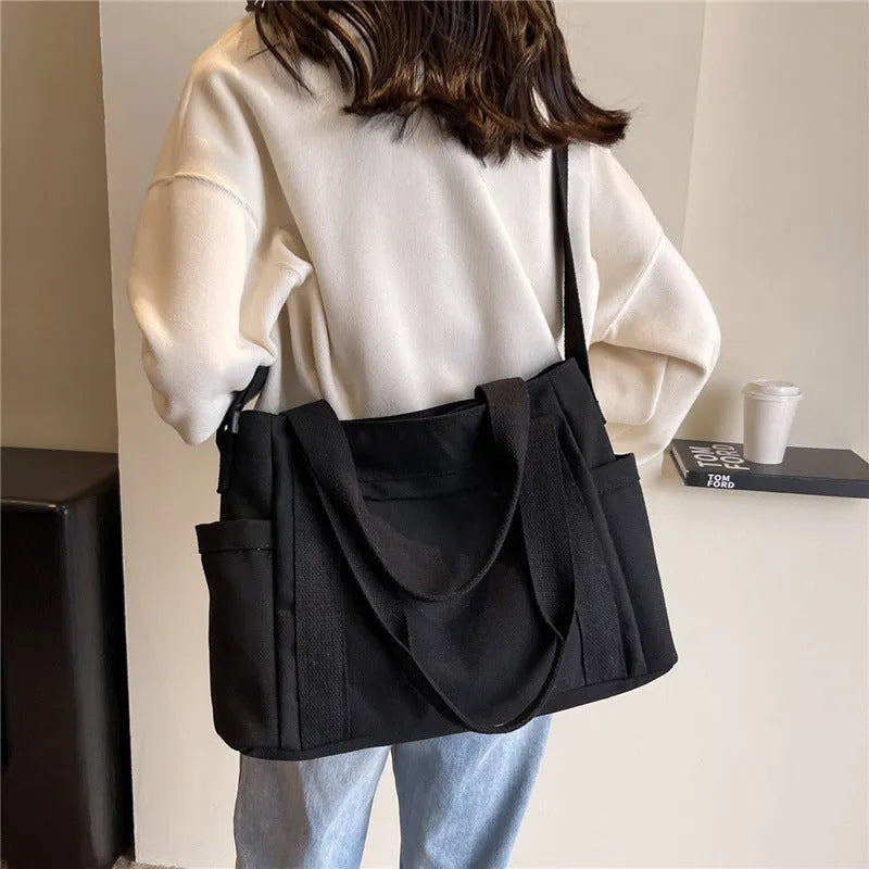 Women's large capacity canvas shoulder bag in solid colour with outer pocket and internal phone compartment