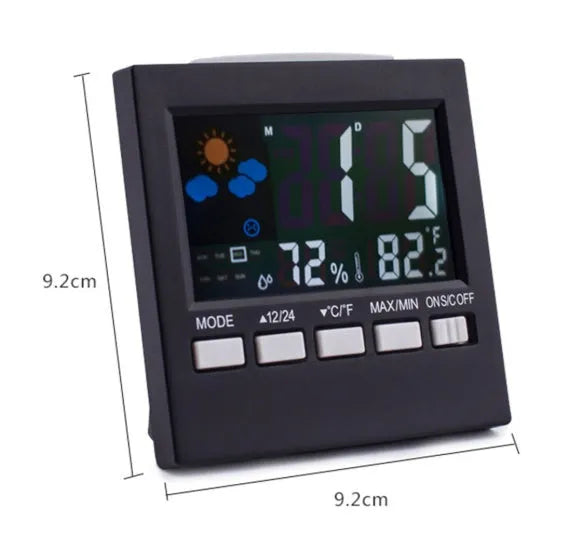 Black digital alarm clock thermometer displaying temperature and time on a desk