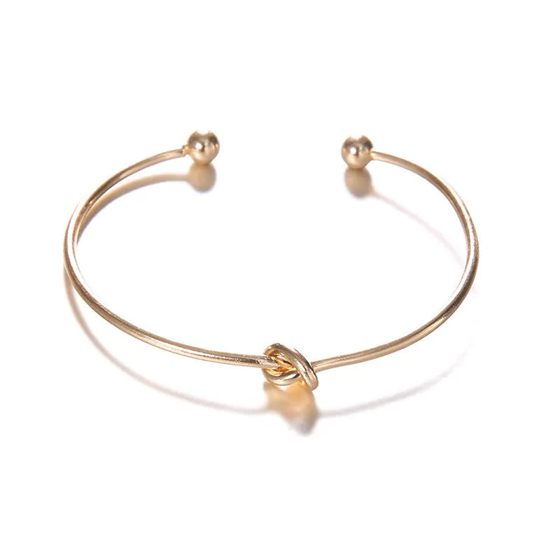 Gold-coloured women's vintage cuff bracelet with arrow and knot design in electroplated alloy