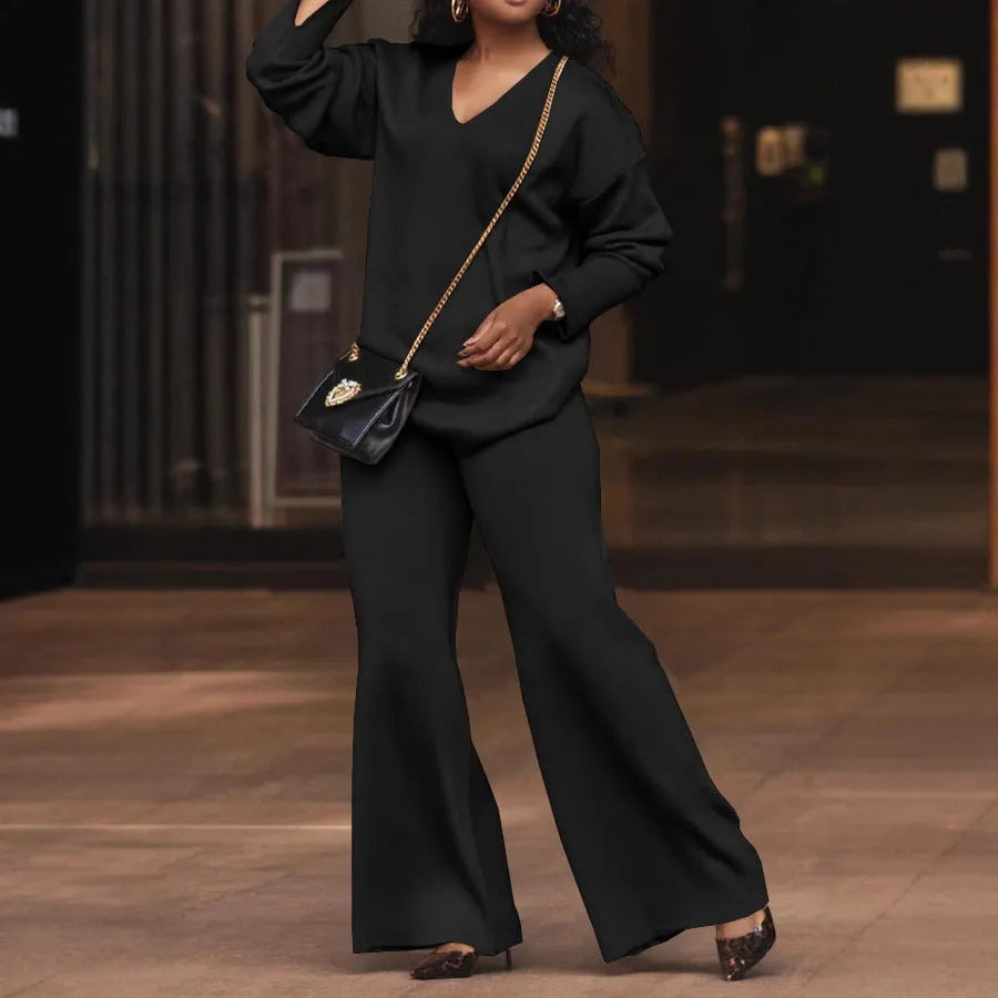 Brown women's suede two-piece suit with split sleeves and matching trousers on a hanger.